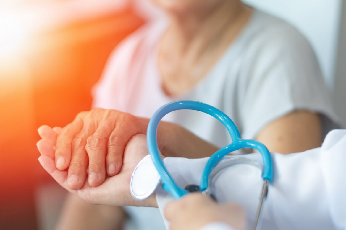 Elderly Female Hand Holding Hand Of Young Caregiver At Nursing